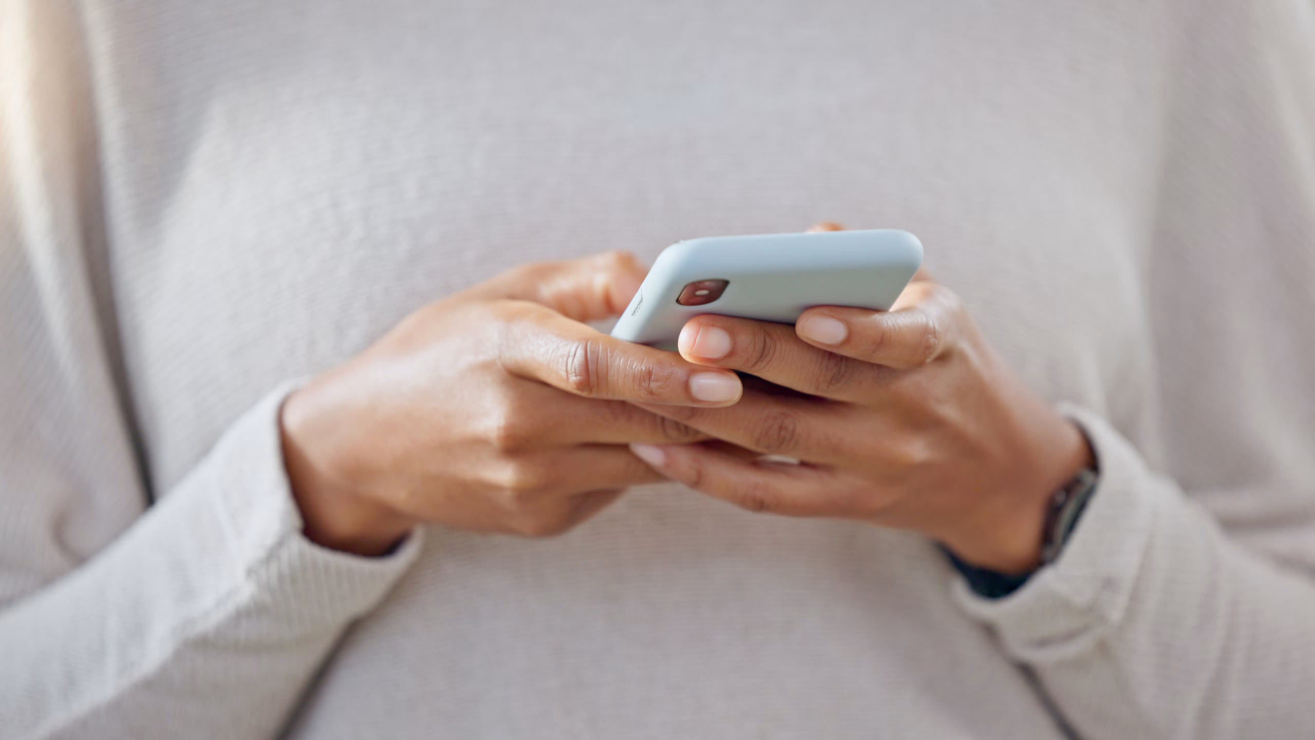 Person using a smartphone with both hands, typing or browsing.